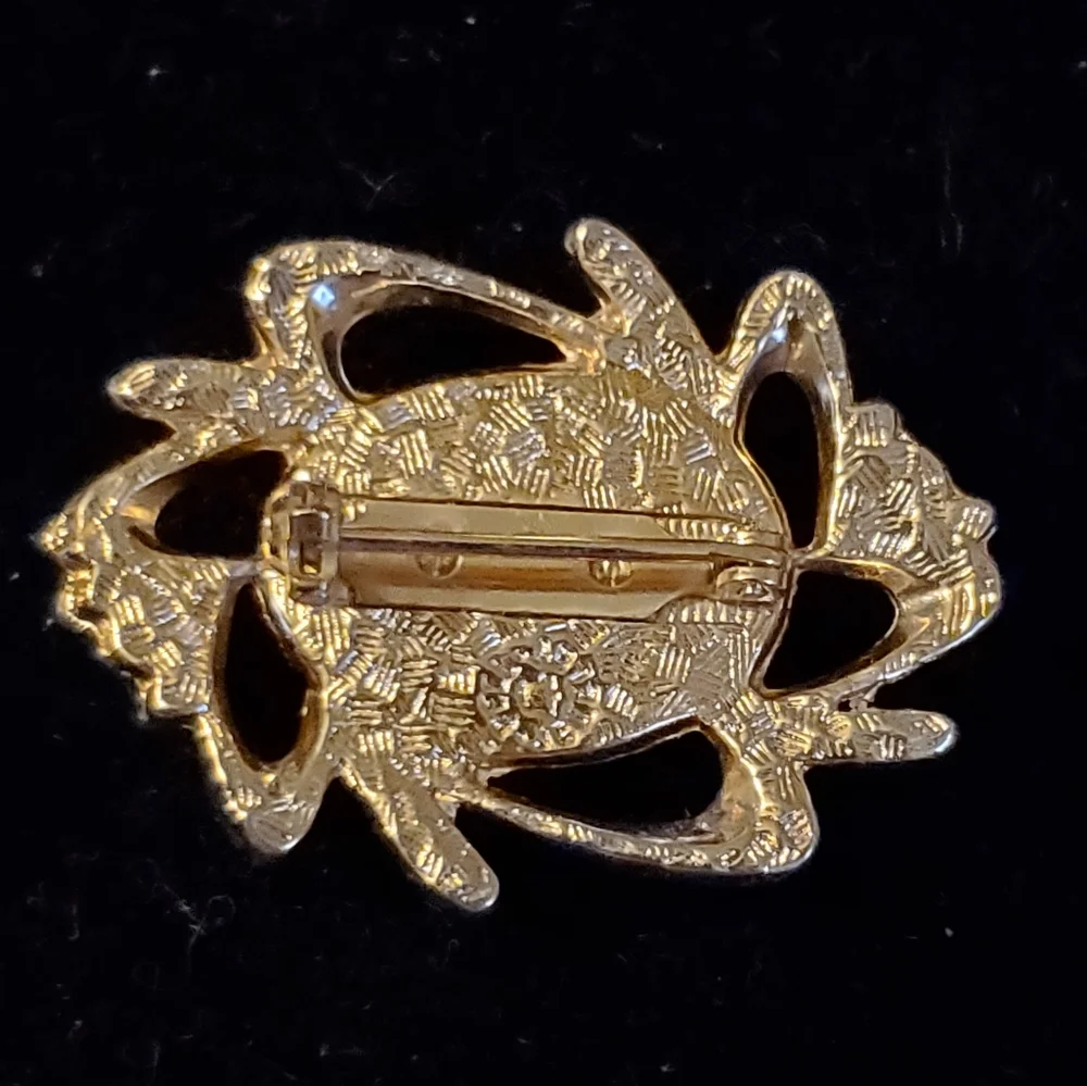 Goldtone brooch with rust colored glittery center stone